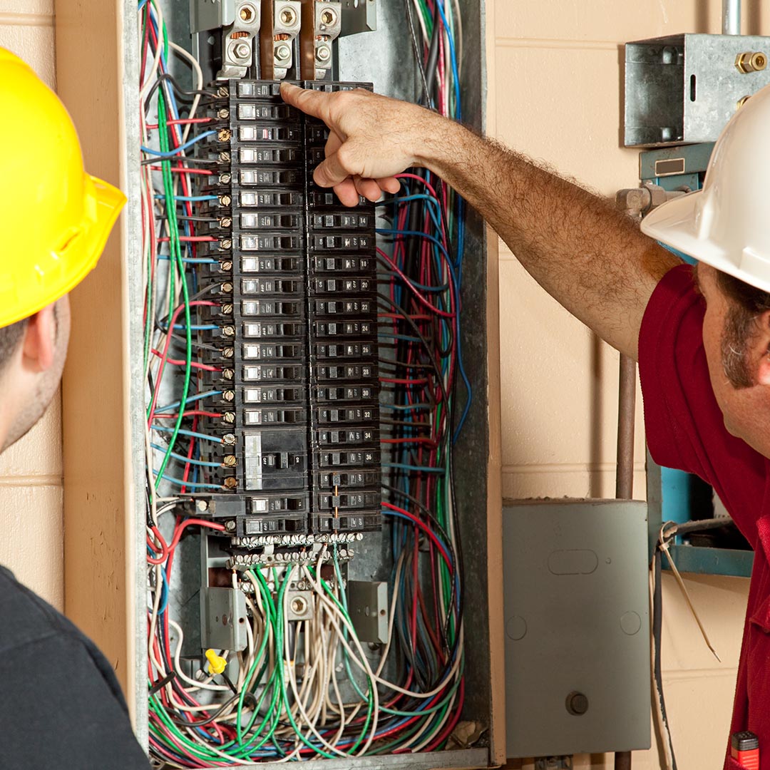 construction working and electrician looking at an electrical panel